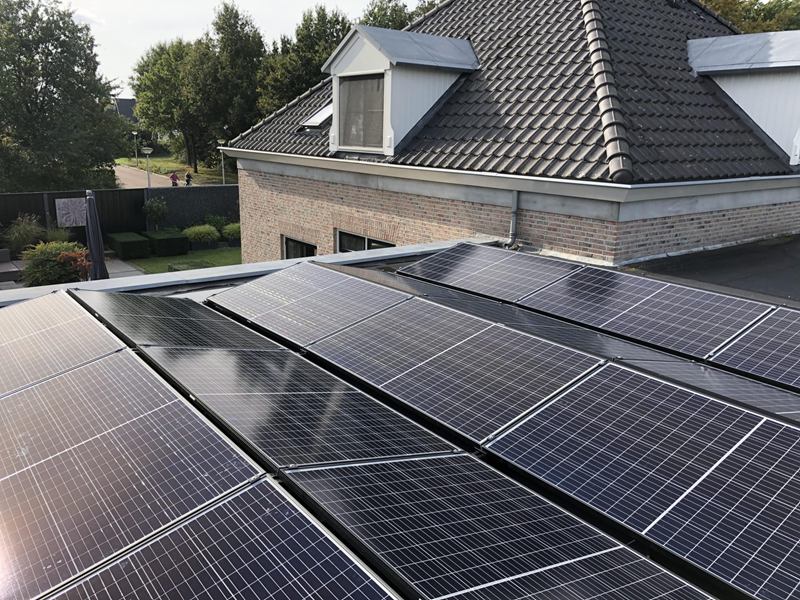 Zonnepanelen op een plat dak naast een woning