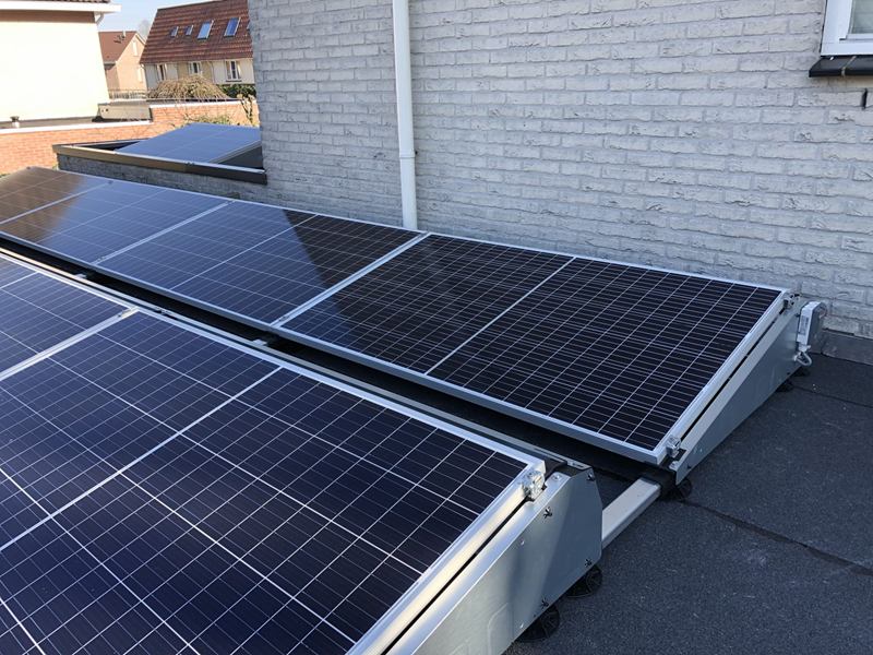 Zonnepanelen op een plat dak tegen een gevel